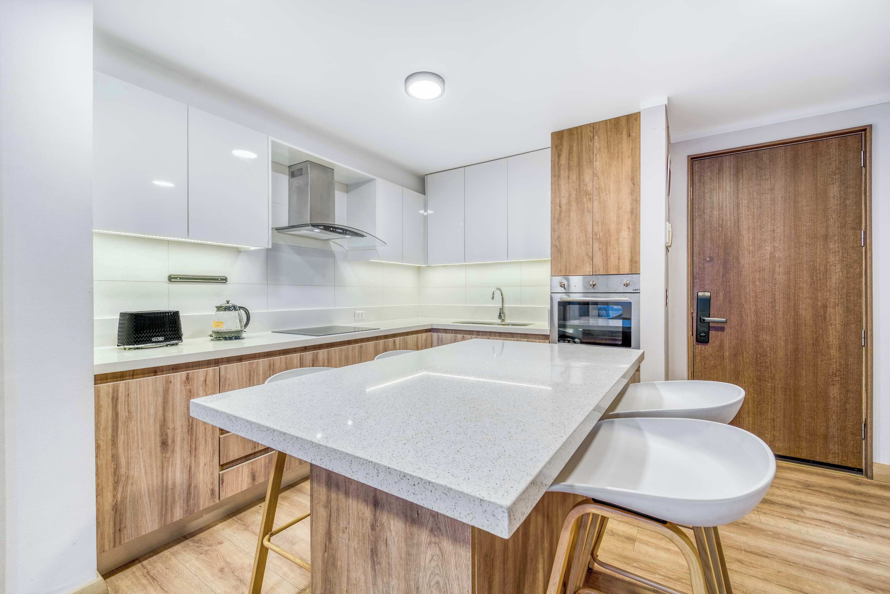 A modern kitchen with a central island, wooden cabinets, and a built-in oven.