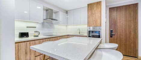 A modern kitchen with a central island, wooden cabinets, and a built-in oven.