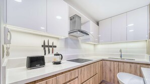 A modern kitchen with white cabinets, a built-in oven, a coffee maker, and a kettle. - Infinite Coast 2BR with pool, gym & free parking (Viña del Mar)