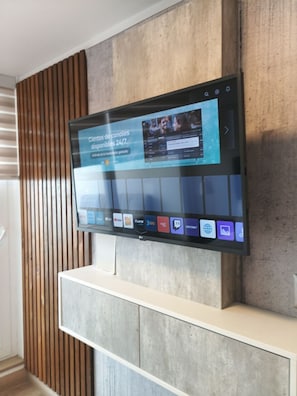 A flat-screen TV mounted on a wall with a wooden slat design, displaying a streaming service interface.