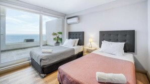A hotel room with two beds, a large window with a view, and an air conditioning unit. - Infinite Coast 2BR with pool, gym & free parking (Viña del Mar)