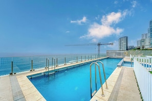 A swimming pool with a view of the ocean and a construction crane in the background.