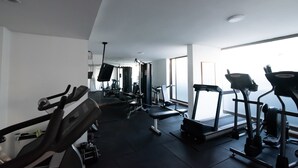 A modern gym with treadmills, stationary bikes, and weight machines. - La Gloria Home - Comfort and City Views (Las Condes)