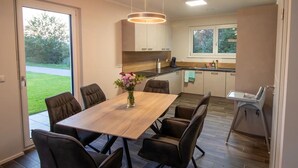 A modern kitchen with dark wood flooring, a central island, and a dining area with a wooden table and chairs.