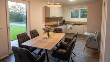 Eine moderne Küche mit dunklem Holzboden, einer zentralen Kochinsel und einem Essbereich mit einem Holztisch und Stühlen.