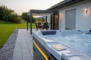 Un bain à remous avec une pergola, une terrasse avec des chaises et une vue sur l’extérieur.