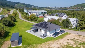 A modern house with solar panels, a covered patio, and a car parked in the driveway.