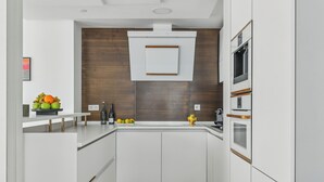 Una cocina moderna con armarios blancos, una pared decorativa de madera y un horno empotrado.