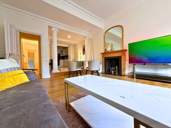 Un salon avec un canapé, une table basse, un téléviseur et une cheminée.