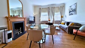 Een woonkamer met een open haard, een ronde glazen tafel, een bank en een televisie.