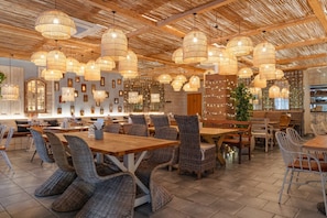 A restaurant with wicker furniture, wooden tables, and hanging wicker chandeliers. - 2b2b Apt Park + River + Balcony (London)