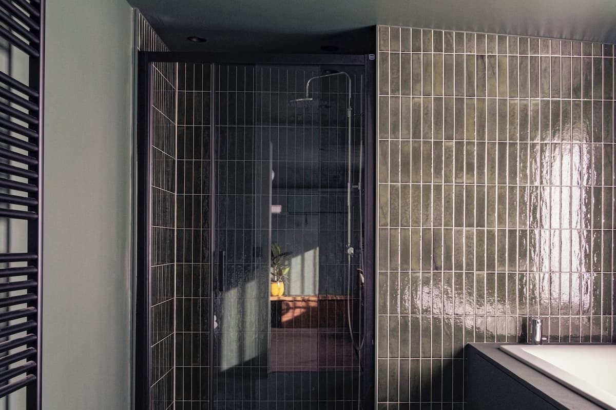 Un baño moderno con cabina de ducha de vidrio, pared con azulejos y ventana.