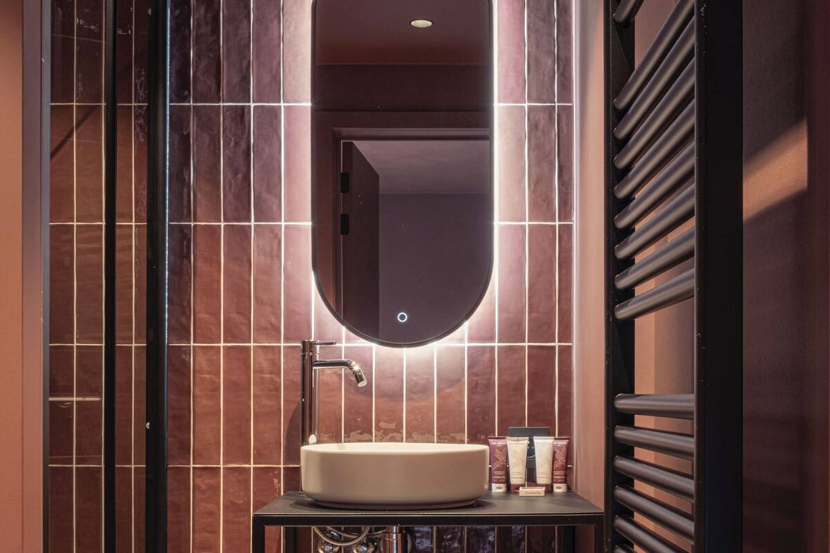 Un baño moderno con cabina de ducha de vidrio, tocador con espejo y perchero para toallas.