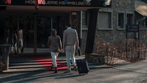 En hotellentrén med en fasad av sten, en röd matta och en skylt som visar var receptionen finns.