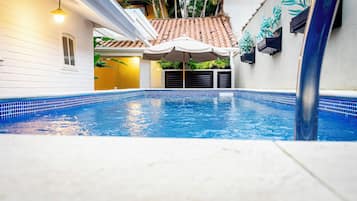 Una piscina al aire libre, sillones reclinables de piscina