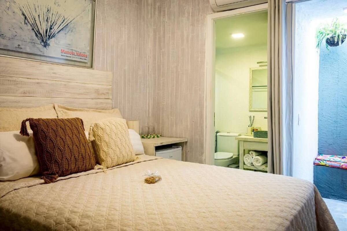 A bedroom with a bed, a nightstand, and a bathroom visible through an open door.