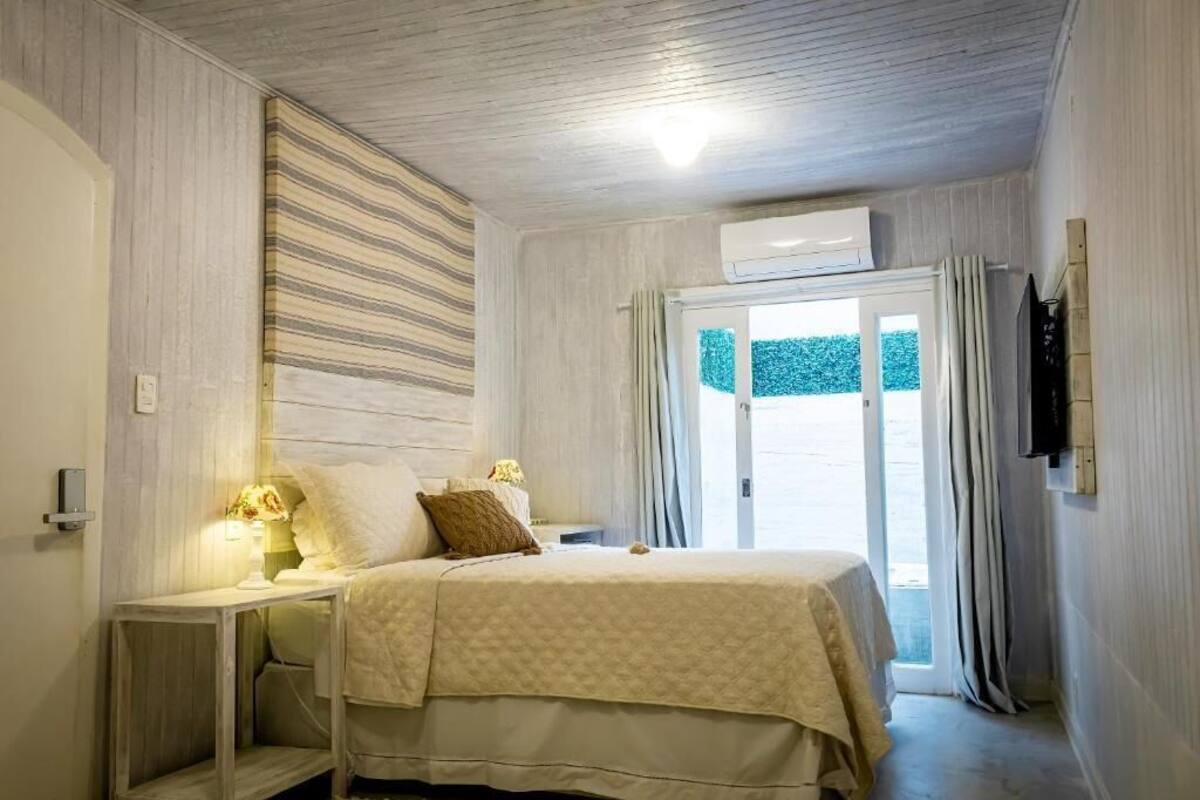 A bedroom with a bed, bedside table, lamp, and a TV mounted on the wall.