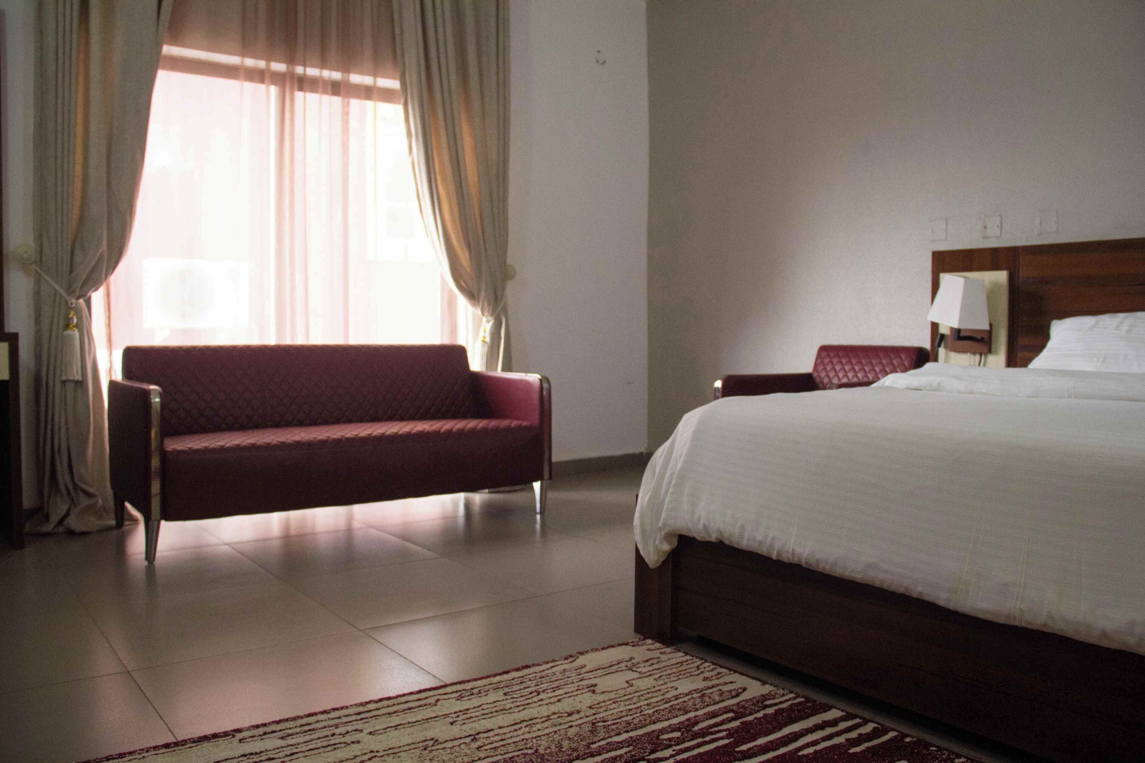 Een hotelkamer met een bed, een slaapbank, een nachtkastje en een lamp.