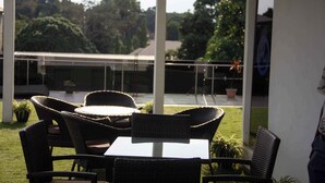 An outdoor seating area with wicker furniture and a view of a building and trees. - Uranium Continental Hotel (Kaduna)