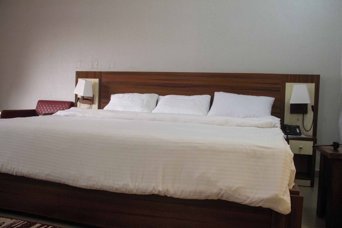 Un lit bien fait, avec du linge de lit blanc, dans une chambre d’hôtel.