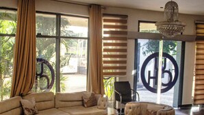 A spacious living room with a sectional sofa, a round ottoman, and a large rug. - Uranium Continental Hotel (Kaduna)