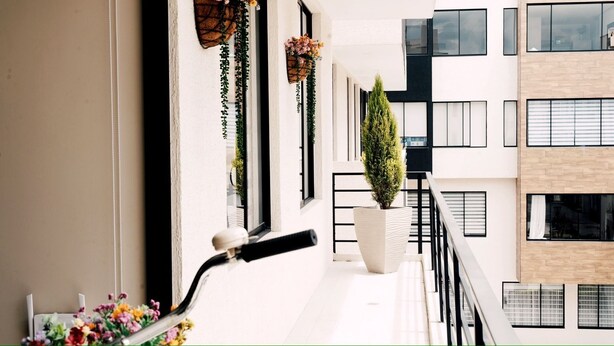 Un edificio moderno con balcones, ventanas amplias y plantas en macetas.