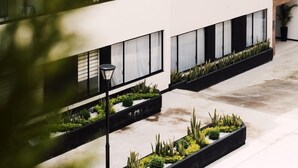 Un edificio de varios pisos con balcones, ventanas amplias y un patio con jardineras.