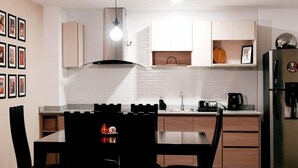 Una cocina moderna con comedor, que incluye una isla central, iluminación colgante y un horno empotrado.
