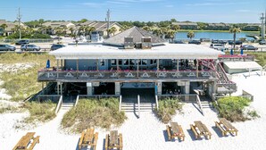 Un edificio frente a la playa con balcón, asientos exteriores y vista al agua.