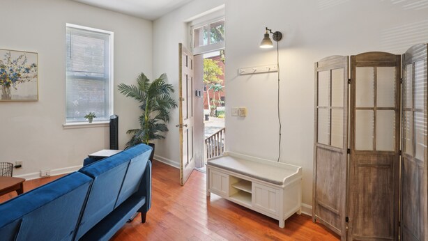 A room with a blue sofa, a white bench, a potted plant, a wall-mounted lamp, and a sliding door. - Charming Soulard Retreat With Historic Character 1 Bedroom Apts (St. Louis)
