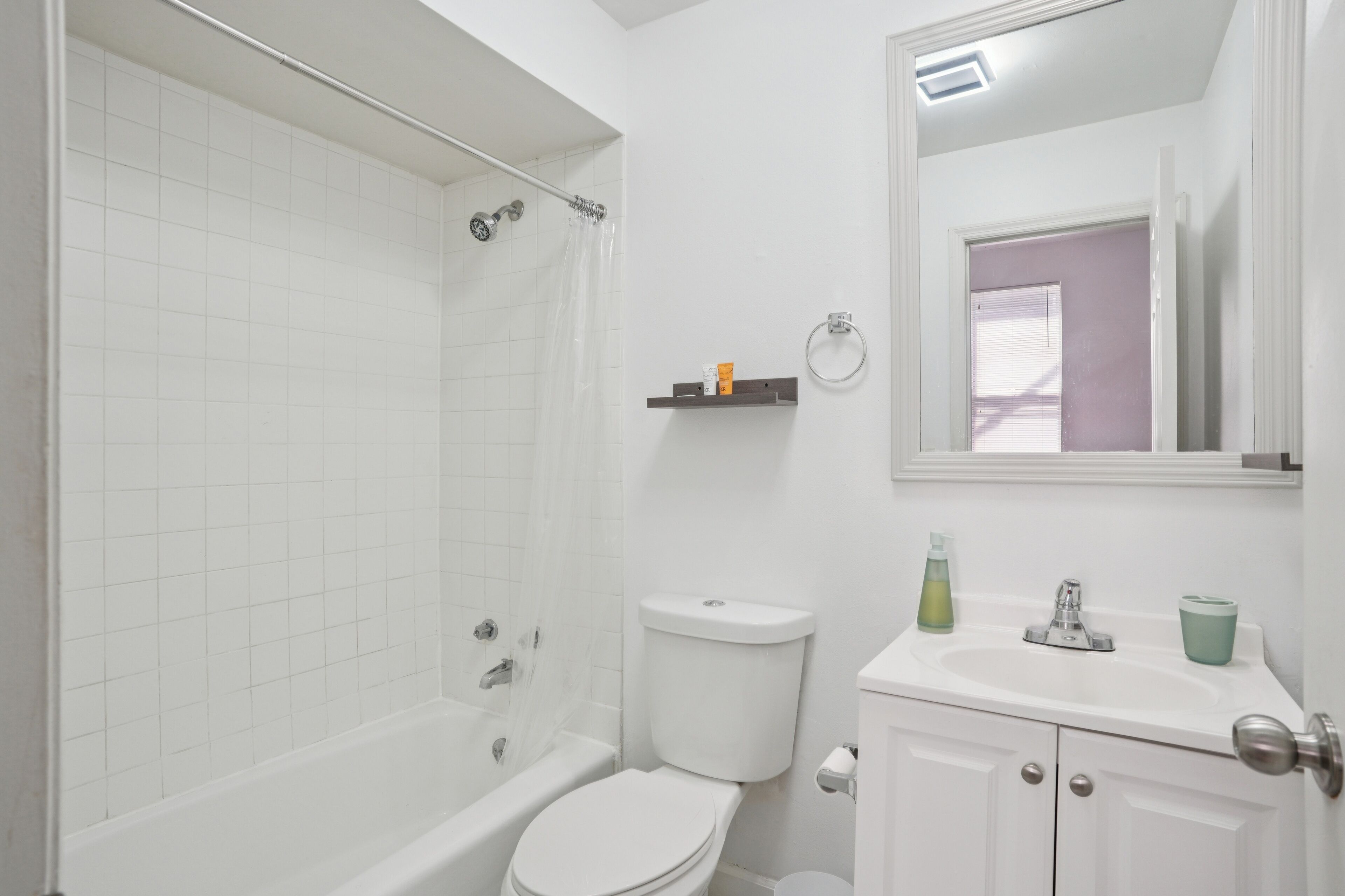 A bathroom with a shower, toilet, sink, and mirror.