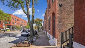 A street with a brick building, a sidewalk, and parked cars. - Charming Soulard Retreat With Historic Character 1 Bedroom Apts (St. Louis)