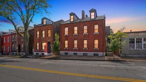A row of red brick buildings with multiple windows and a clear sky. - Charming Soulard Retreat With Historic Character 1 Bedroom Apts (St. Louis)