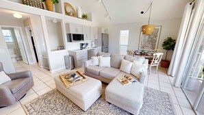 Ein modernes Wohnzimmer mit einem Ecksofa, einem Couchtisch und einem Essbereich mit Tisch und Stühlen.