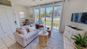 A living room with a sofa, coffee table, TV, and a view of the outdoors.