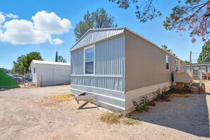 Il s’agit d’une maison mobile de plain-pied, avec une façade en métal ondulé, une porte coulissante et un petit espace porche.