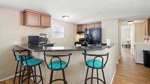Une cuisine dotée d’un îlot central, de tabourets de bar, d’un four à micro-ondes, d’une cuisinière et d’un réfrigérateur.