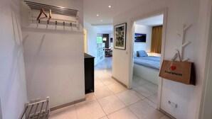 Un passadís d'hotel amb un llit, un penjador i una bossa a la paret.