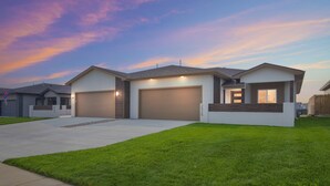 Une maison moderne à deux étages, dotée d’un garage, d’une pelouse bien entretenue et surplombant un ciel dégagé.