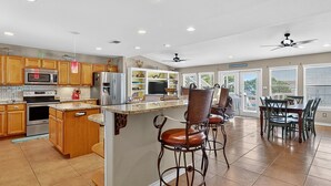 A spacious kitchen with modern appliances, a bar area, and a dining space with a view. - The Blue Pearl Rp6 4 Bedroom Home (Rockport)