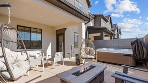 A modern outdoor patio with a fire pit, cushioned chairs, and a hot tub. - Desert Retreat Near Sand Hollow 4 Bedroom Townhouse (Washington)