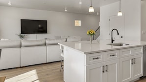 A modern kitchen with white cabinetry, a central island, and pendant lighting. - Desert Retreat Near Sand Hollow 4 Bedroom Townhouse (Washington)