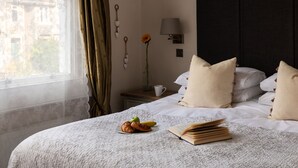 A neatly made bed with pillows, a bedside table with a lamp, a vase with a flower, and a plate with food. - Stylish 4-bedroom Townhouse in the Heart of Bath (Bath)
