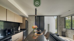A modern kitchen with a central island, a dining area with a sofa, and a view of the outdoors. - Stylish 1BR Apartment in Roma Norte Near Condesa (Mexico City)