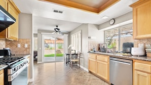 A spacious kitchen with a stove, dishwasher, and a dining area with a table and chairs.