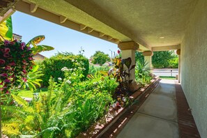 Une allée couverte, avec un jardin d’un côté et une vue sur la rue de l’autre.