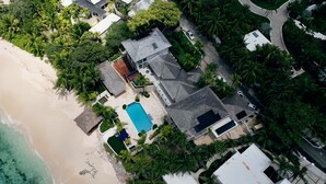 An aerial view of a coastal property with a swimming pool, beach access, and lush greenery. - Newly Renovated Notos Cove Villa Property (Nassau)