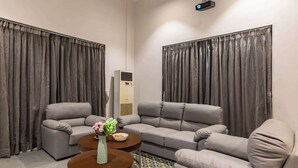Ein modernes Wohnzimmer mit einer Eckcouch, einem Couchtisch und einer großen Klimaanlage.