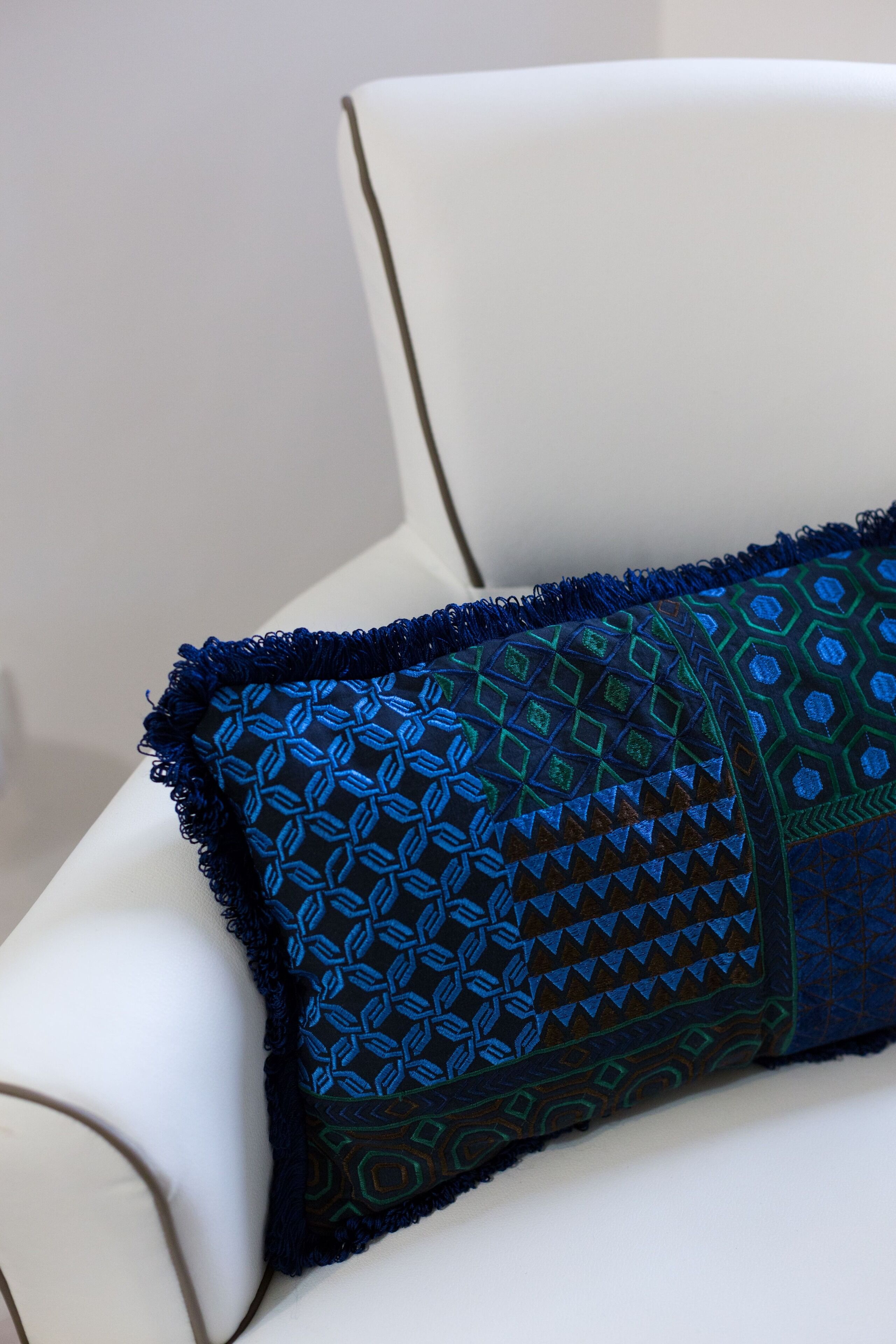 Une chaise blanche avec un coussin décoratif bleu à motifs.