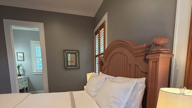 A neatly made bed with a wooden headboard, a bedside table with a lamp, and a mirror on the wall.